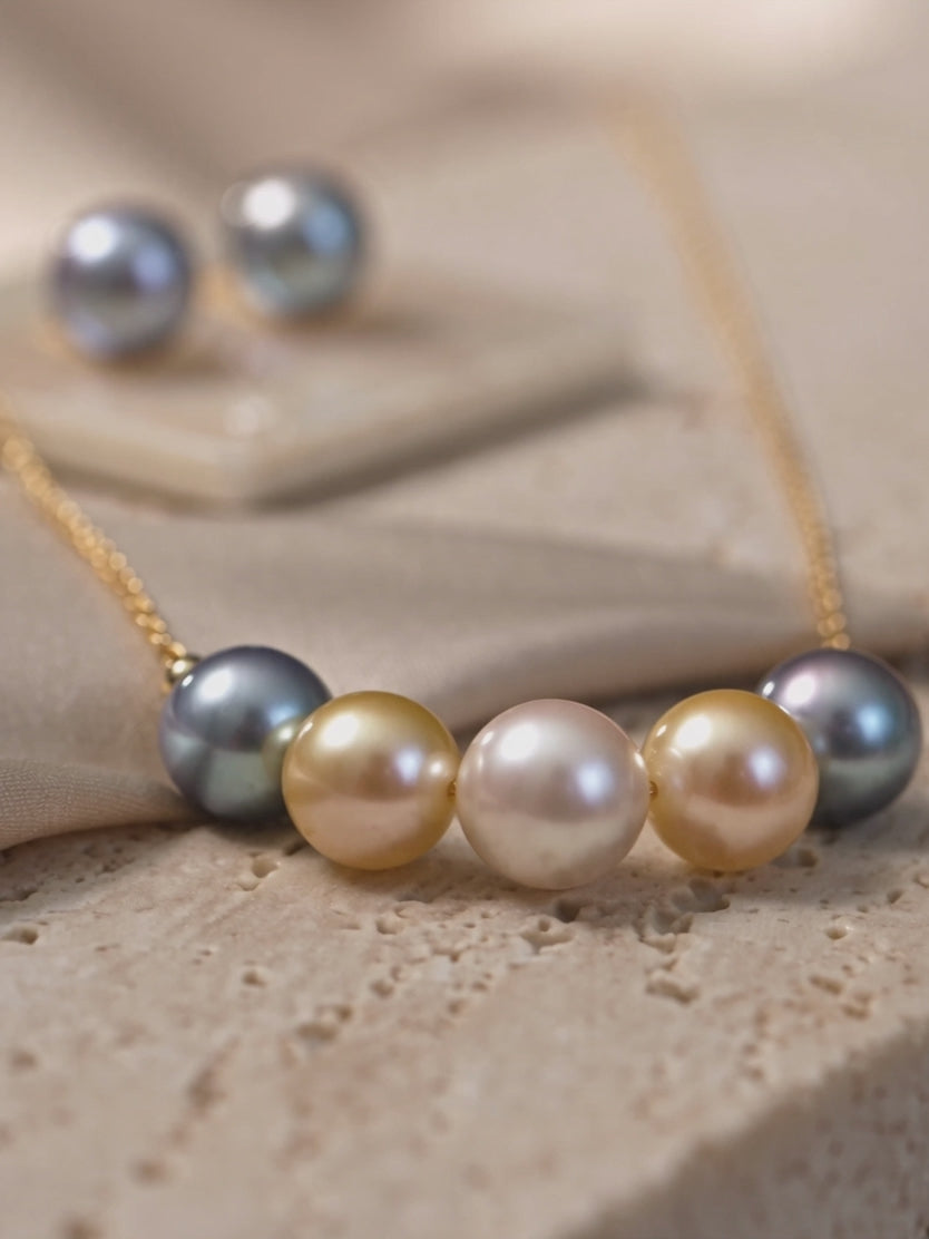 Multi-color South Sea and Tahitian pearl pendant necklace on a gold chain, featuring white, golden, and silver-grey pearls.