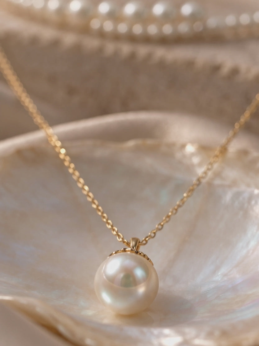 Anna Borjigin single white pearl pendant necklace on a fine gold chain displayed inside a mother-of-pearl oyster shell.