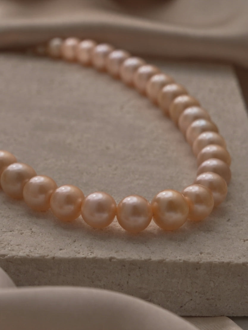 Anna Borjigin classic peach pearl strand necklace featuring lustrous round pearls displayed on natural stone.