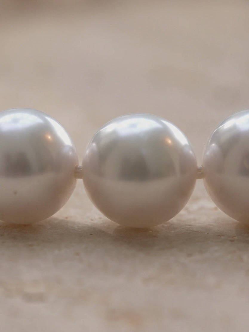 High-luster round white pearl necklace showcasing smooth surface quality and silk-knotted detailing.