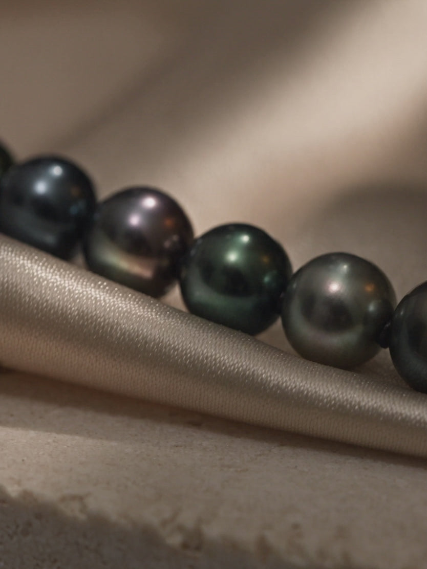 Black pearl necklace with peacock overtones – close-up product video showcasing round pearl luster and surface quality.