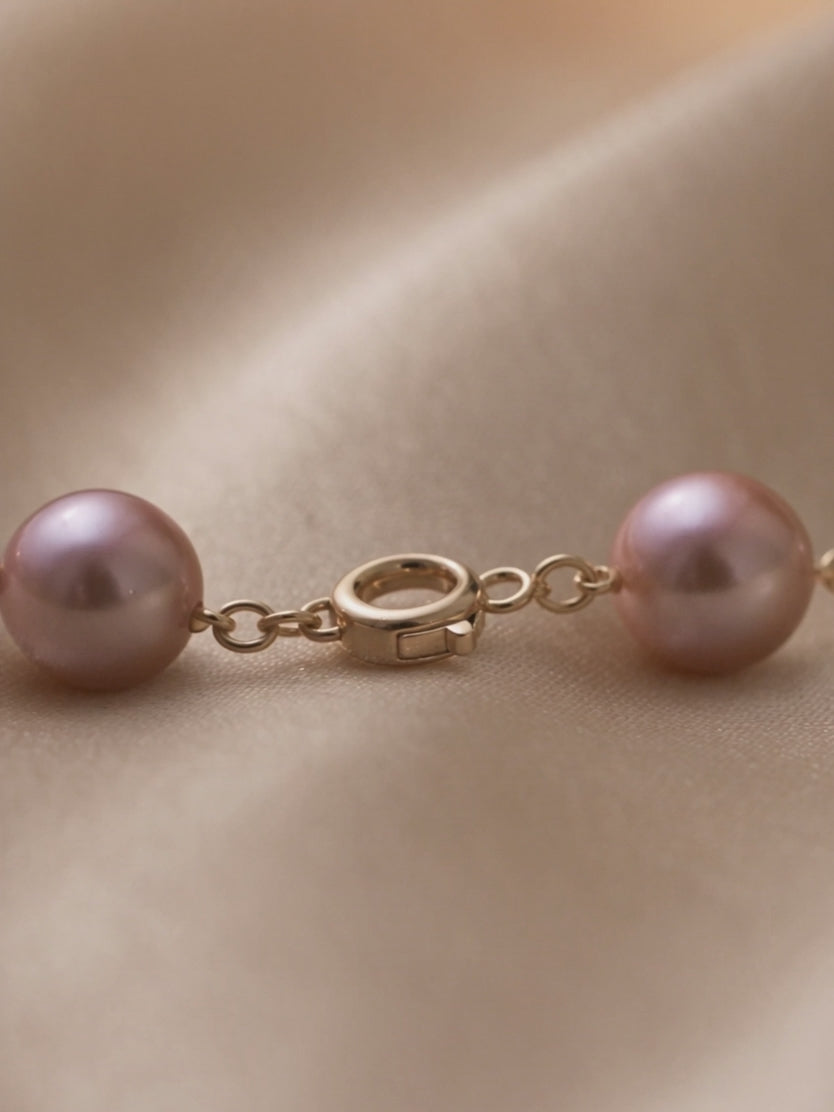 Anna Borjigin pink pearl necklace detail showcasing the round gold clasp and delicate gold chain links.