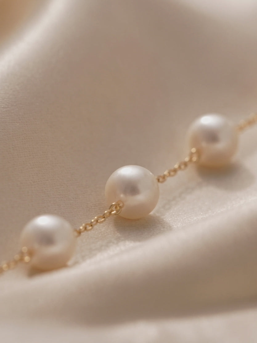 Anna Borjigin white pearl station necklace detail showcasing round white pearls connected by delicate gold chain links.